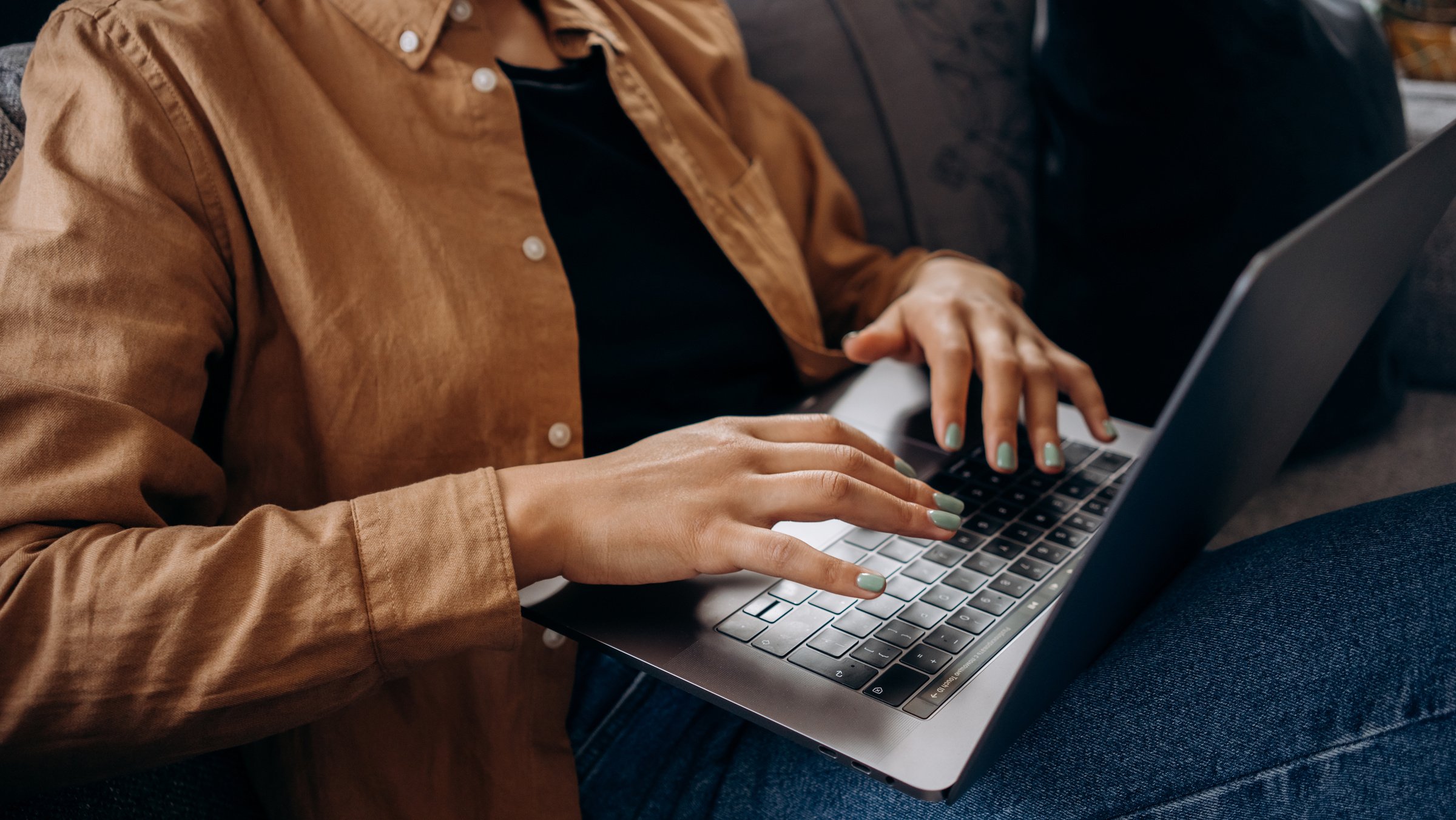 Person in Brown Button Up Shirt is Using a Macbook Pro